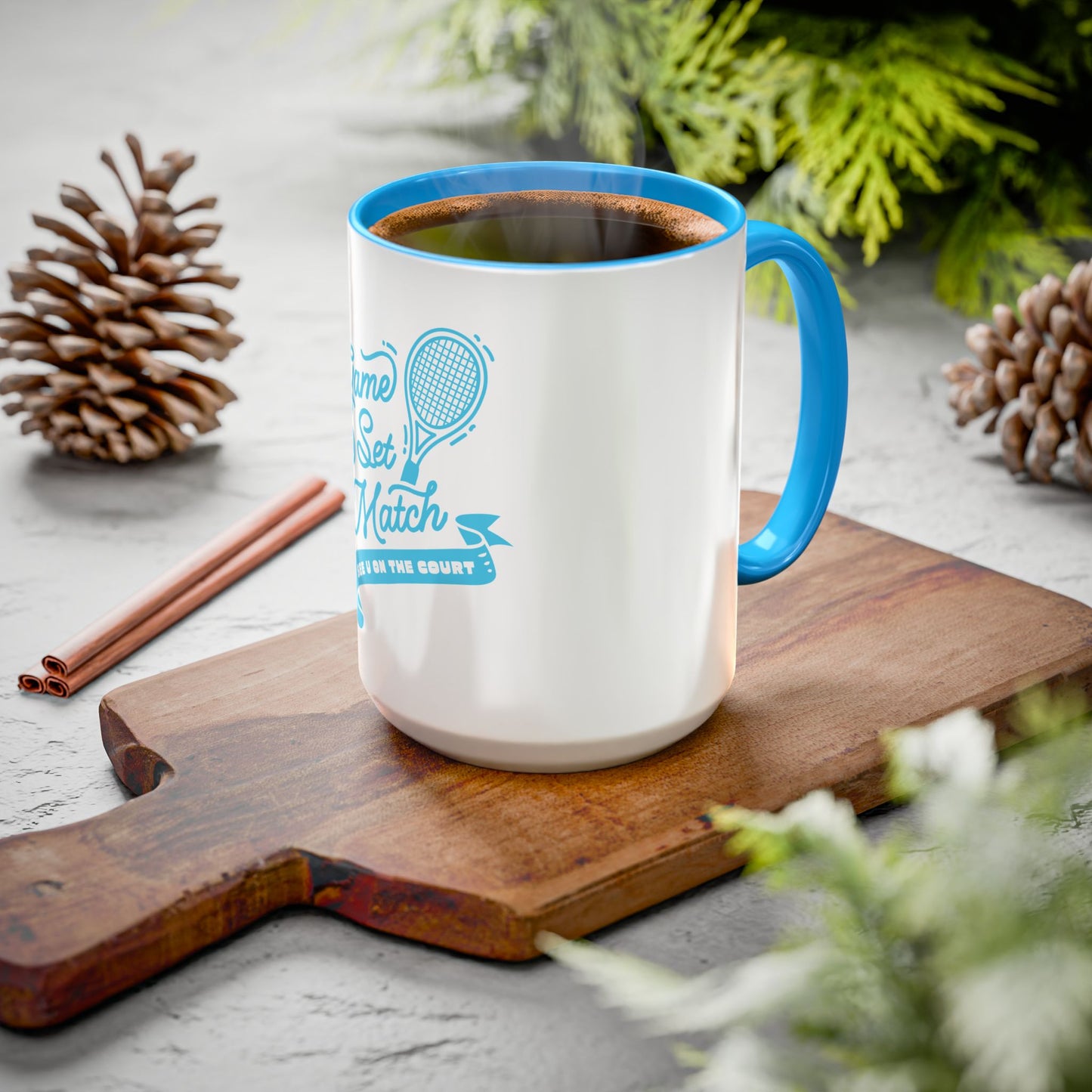 White mug with blue handle and interior, filled with a beverage, on a wooden cutting board with decorative elements.
