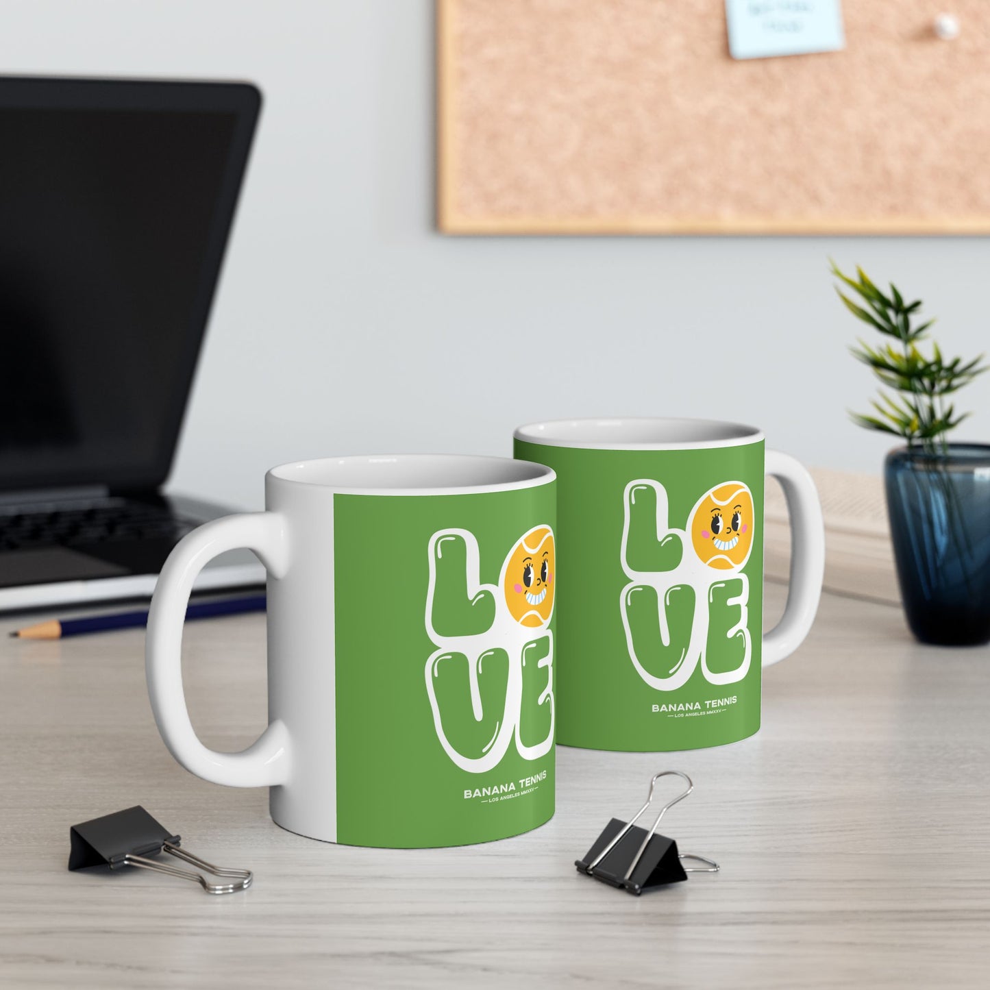Two green mugs with 'LOVE' design on a desk with office supplies.