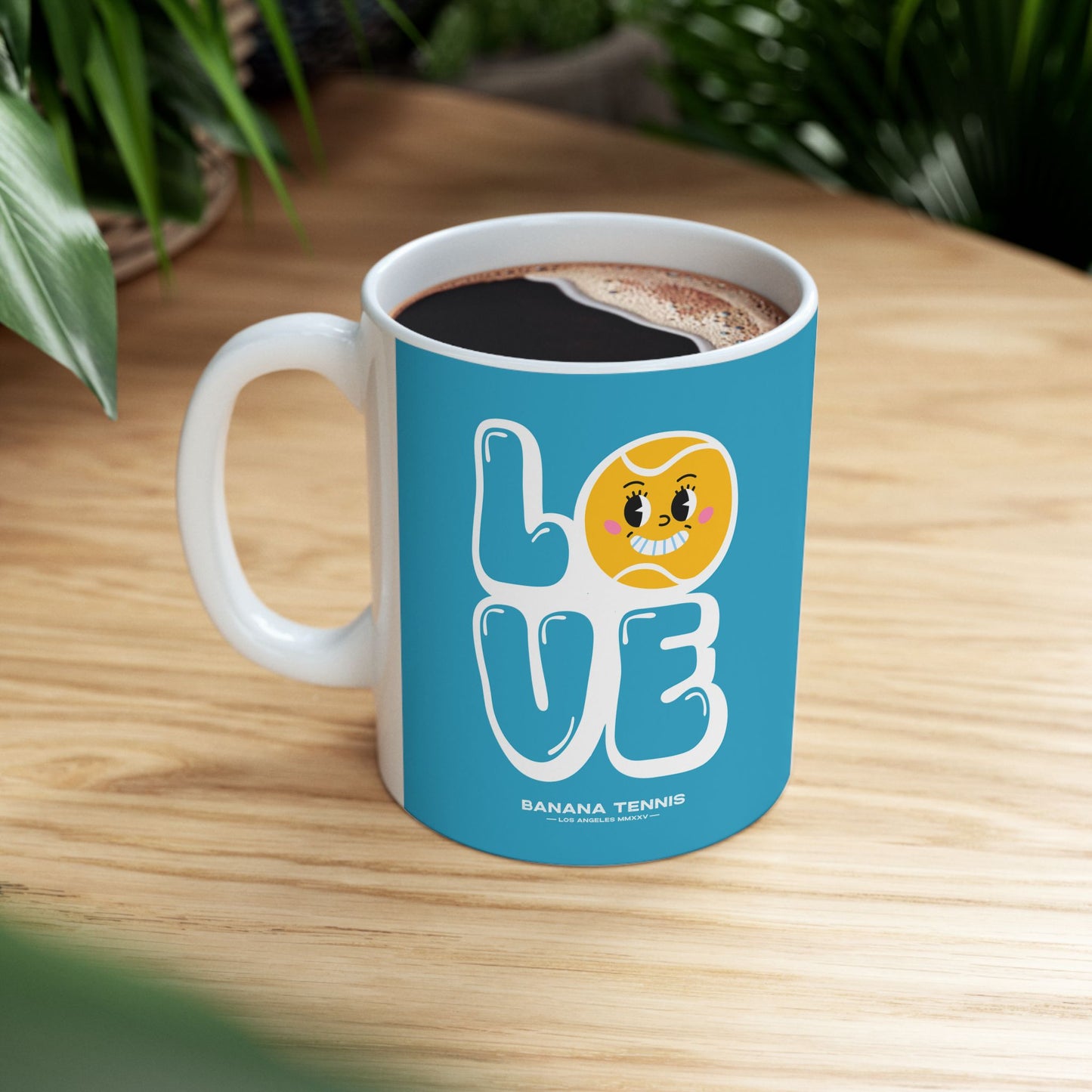 Blue mug with 'LOVE' and banana tennis character on a wooden table