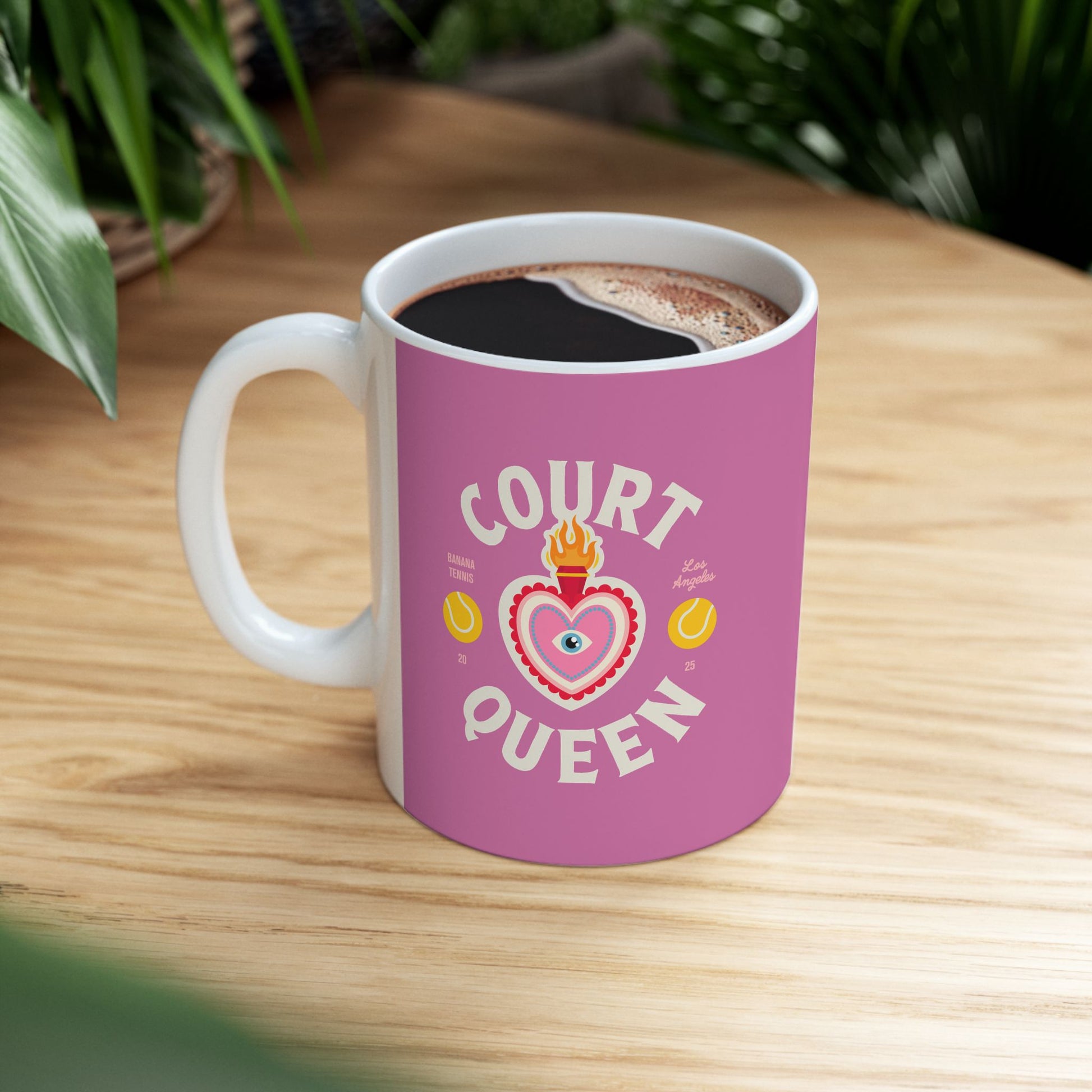Pink mug with 'Court Queen' design on a wooden table