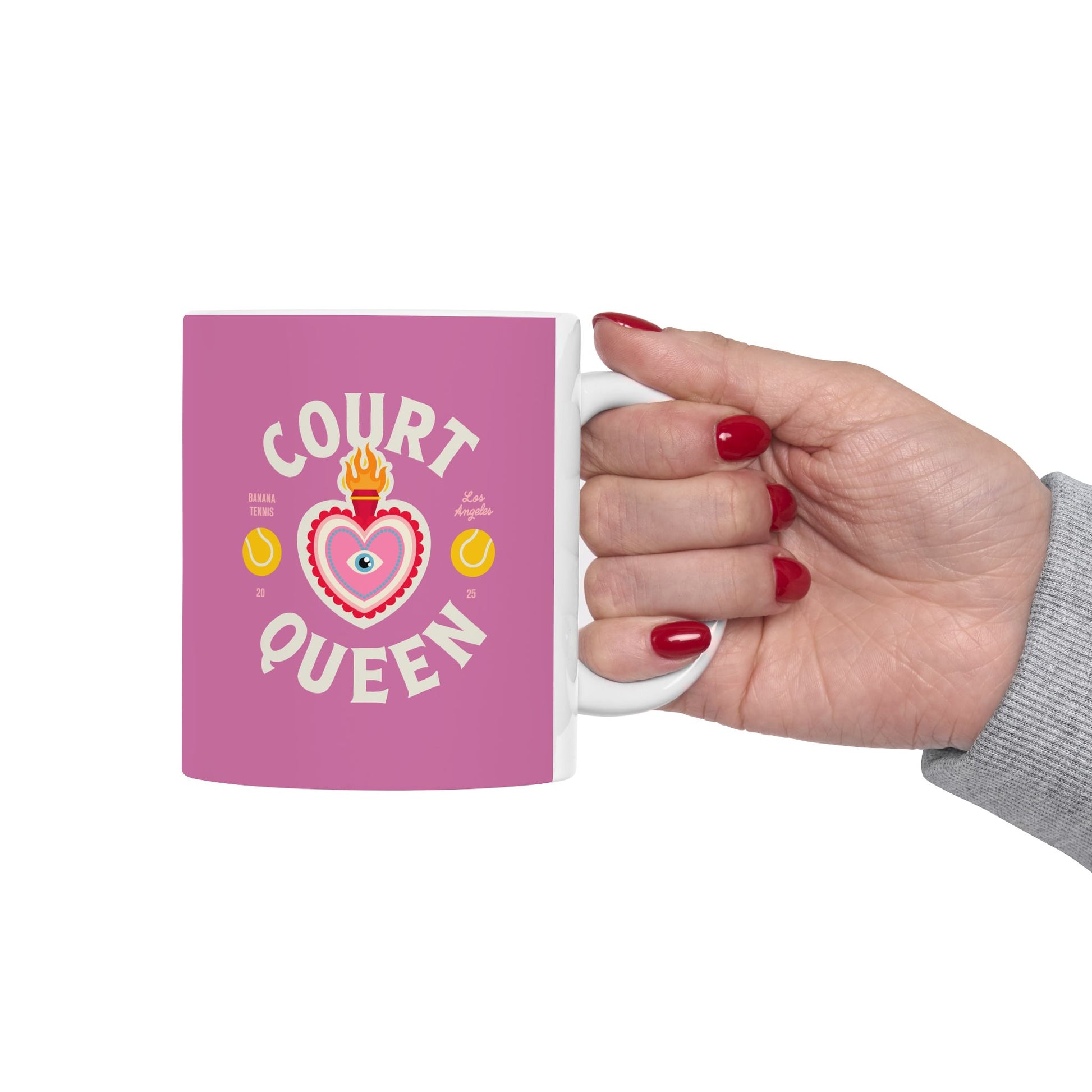 Pink mug with 'Court Queen' design held by a hand with red nail polish on a white background