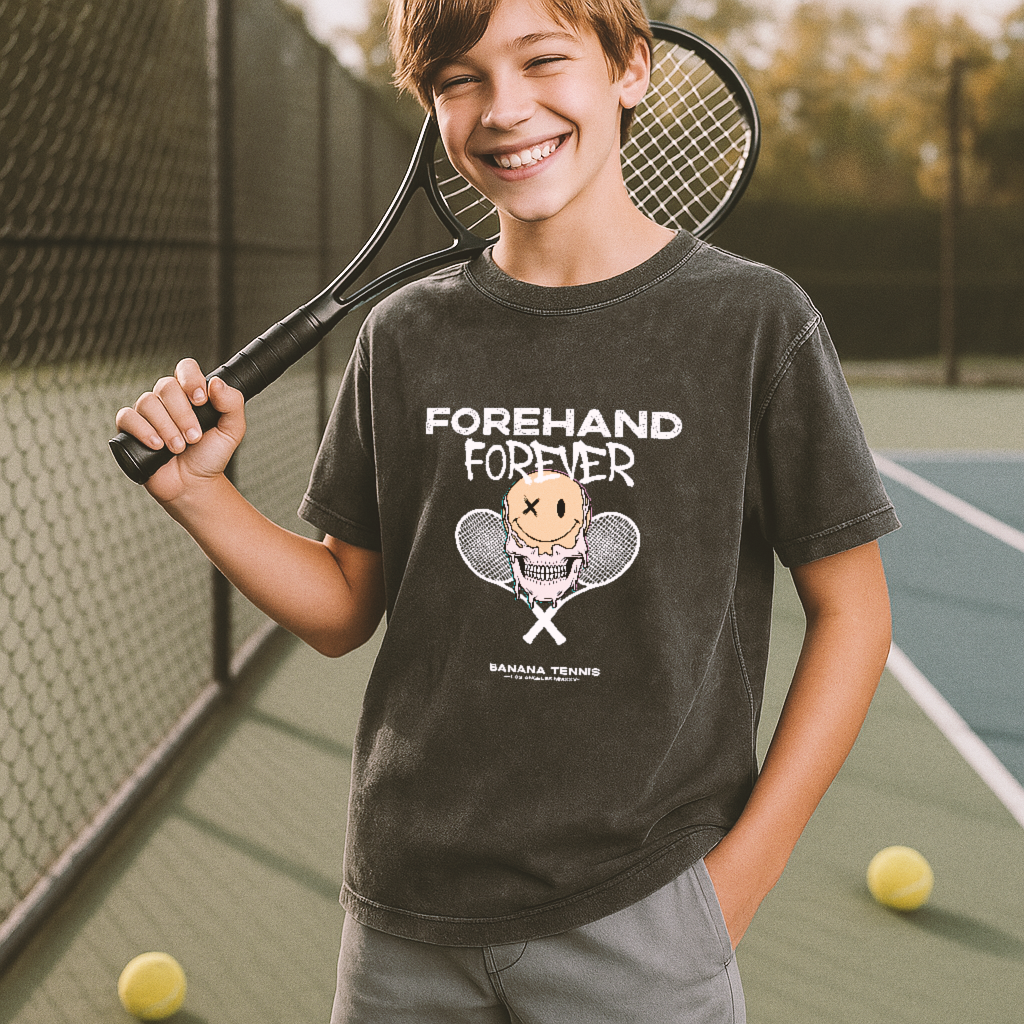 Child holding a tennis racket and wearing a 'Forehand Forever' t-shirt on a tennis court.