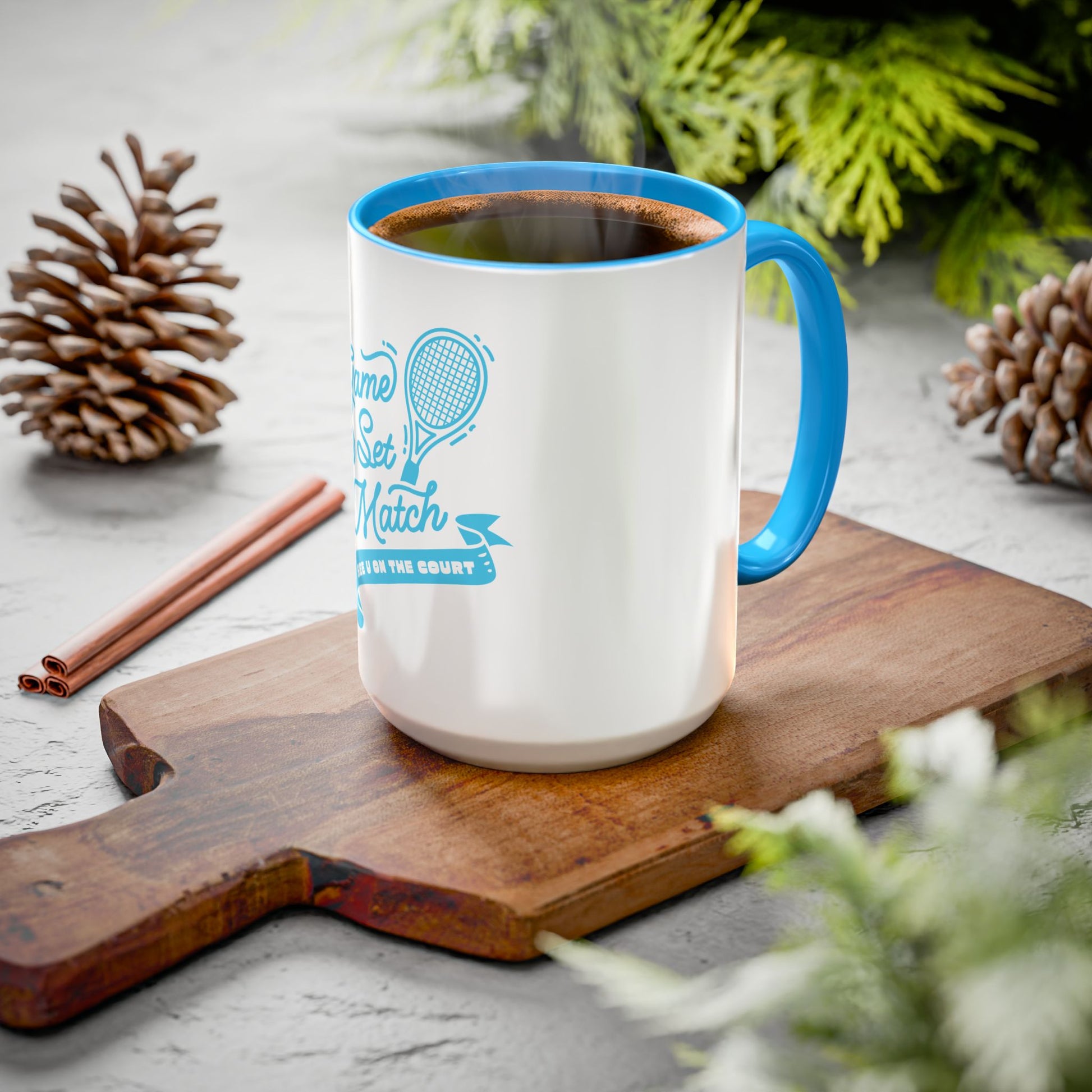 White mug with blue handle and interior, filled with a beverage, on a wooden cutting board with decorative elements.