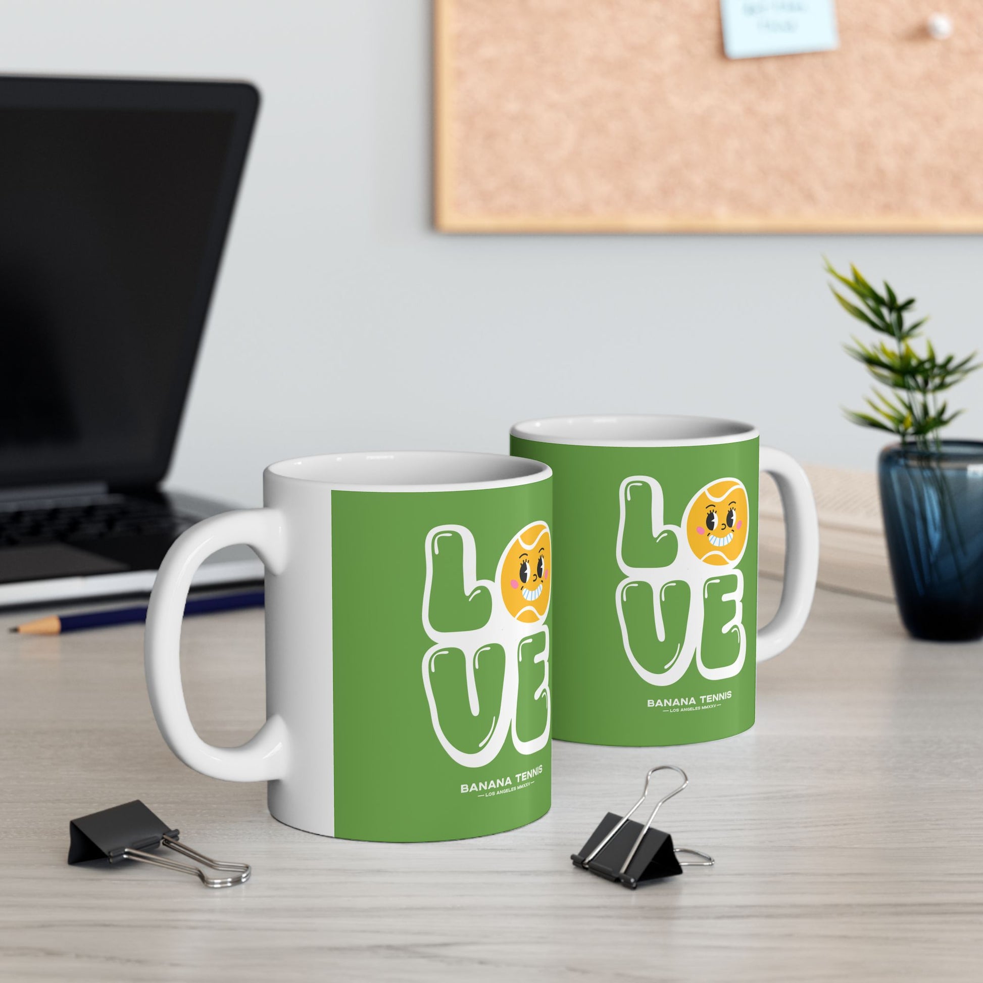 Two green mugs with 'LOVE' design on a desk with office supplies.