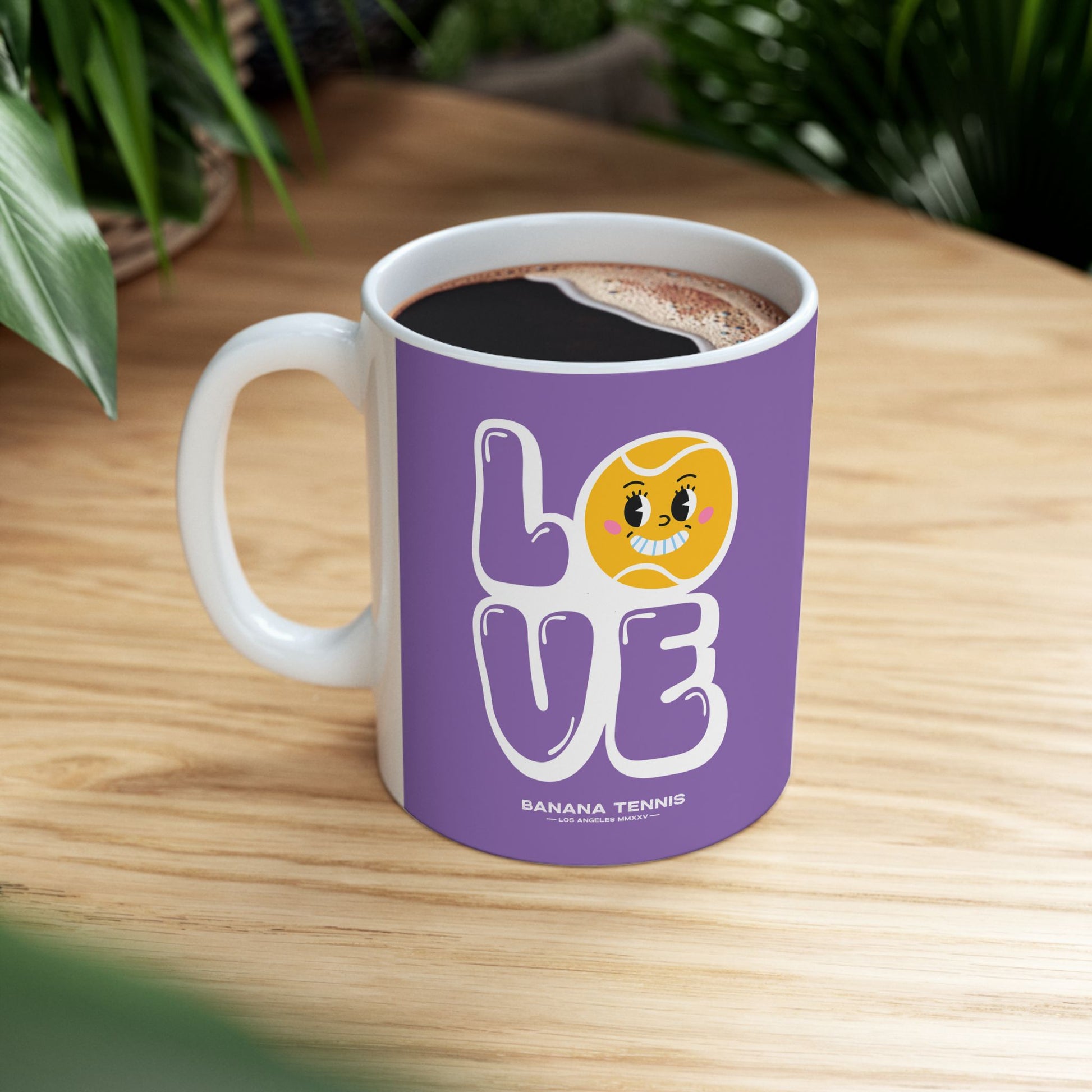 Purple mug with 'LOVE' and tennis ball design on a wooden table