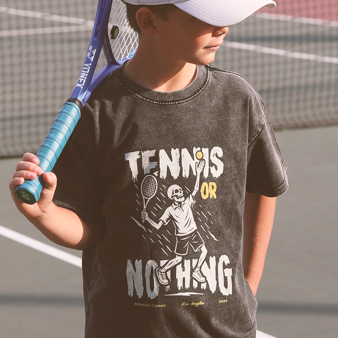 Child wearing a 'Tennis or Nothing' t-shirt on a tennis court
