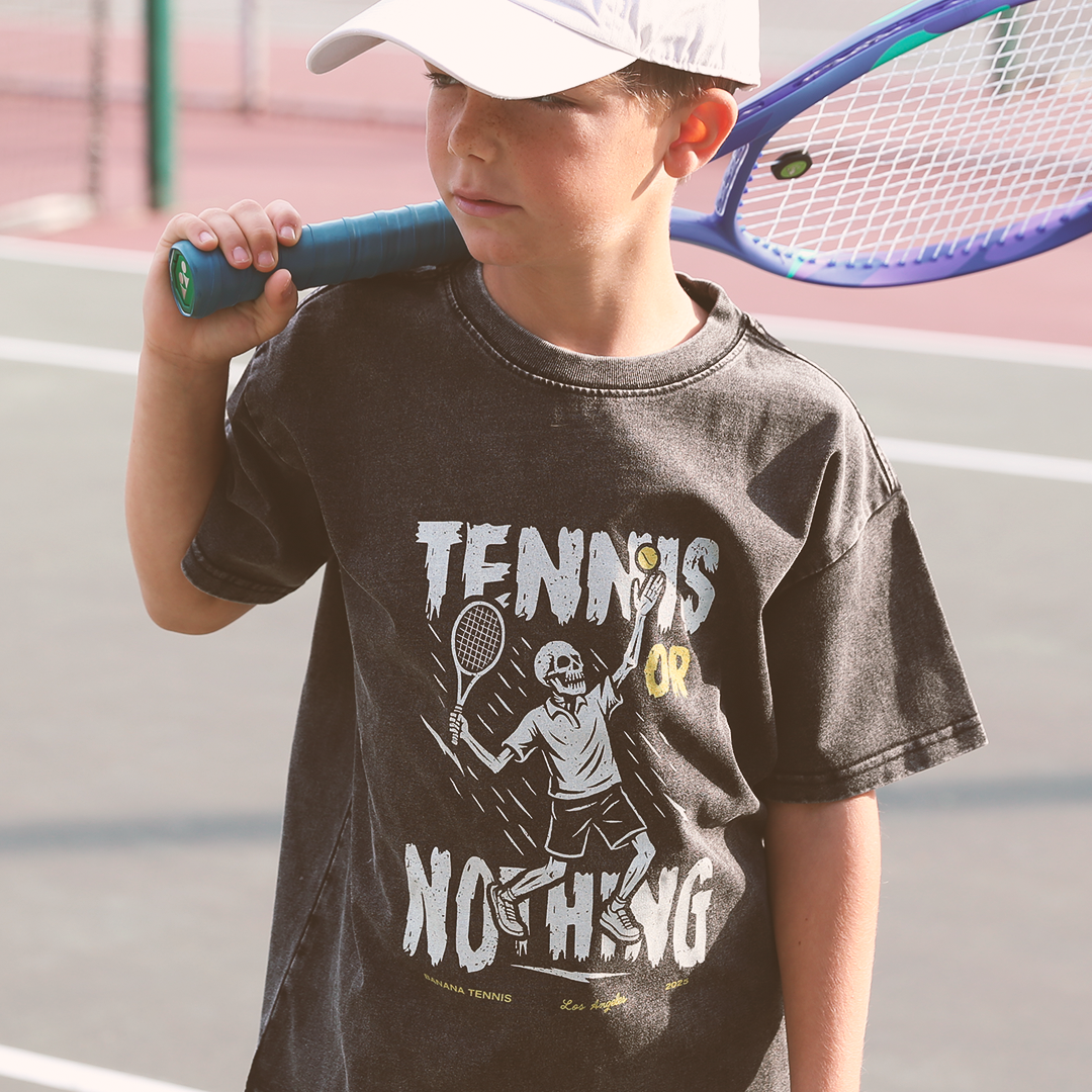 Child wearing a 'Tennis or Nothing' t-shirt on a tennis court