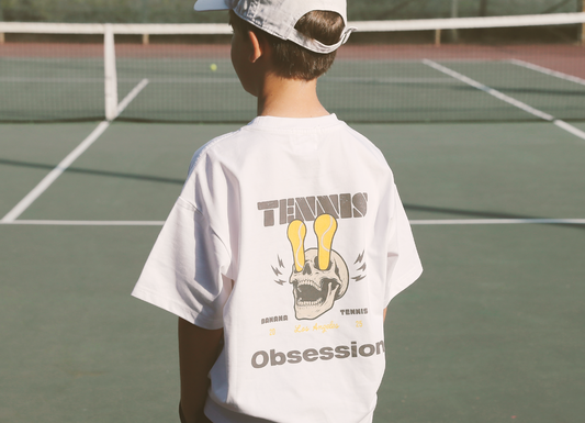 Person wearing a white t-shirt with 'Tennis Obsession' design on a tennis court
